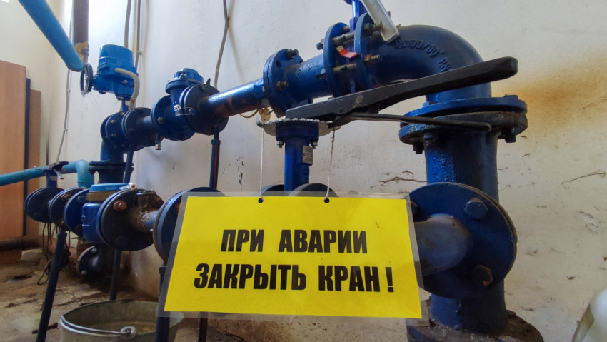 Узел трубопровода с множеством кранов и предупреждающей табличкой