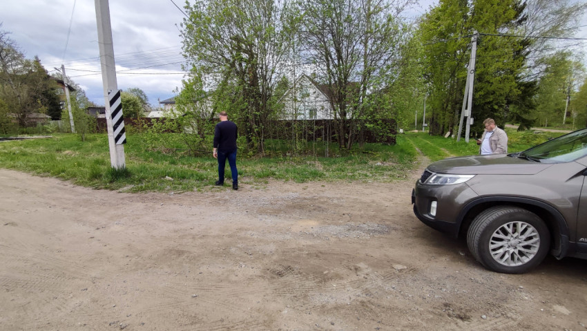 Грунтовая площадка у жилого дома и два человека рядом с автомобилем