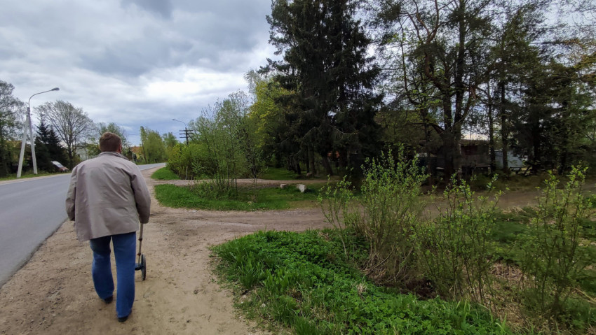 Мужчина с измерительным колесом на обочине загородной дороги