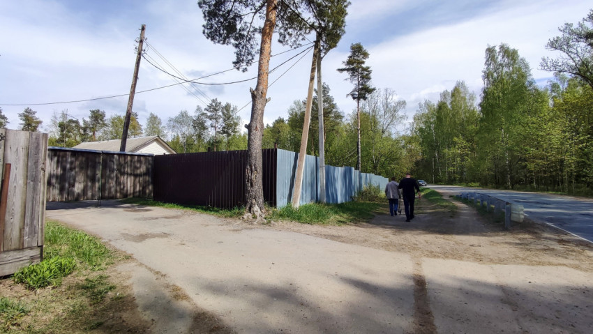 Пешеходы у забора вдоль загородной дороги