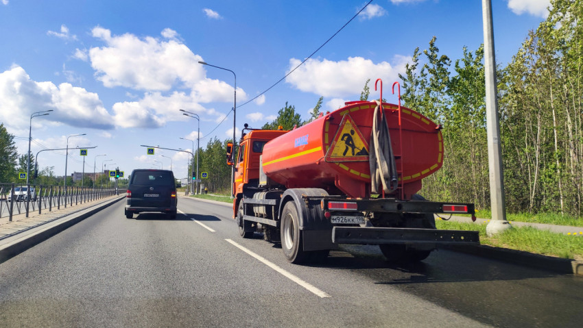 Спецавтомобиль дорожной службы с цистерной на городской дороге