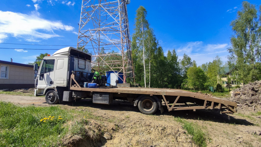 Грузовик с платформой на строительной площадке возле металлической башни