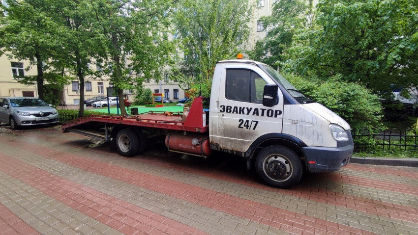 Эвакуатор у жилого дома рядом с детской площадкой