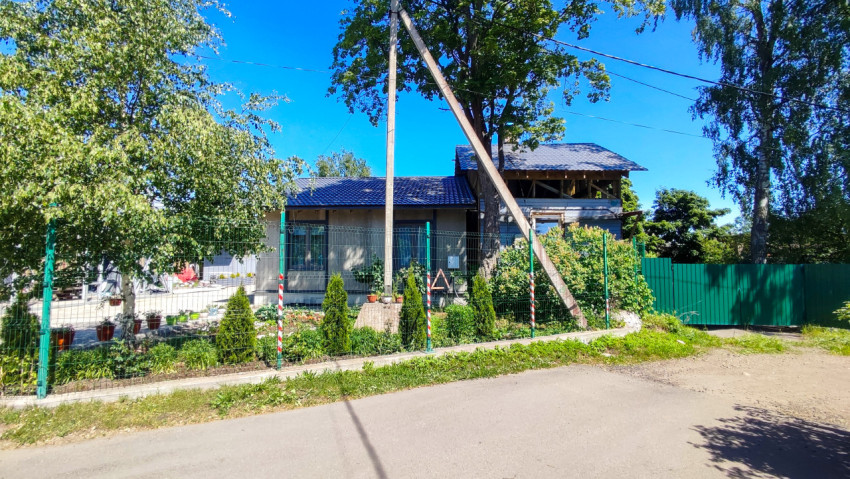 Загородный дом с серым фасадом и металлической крышей за забором
