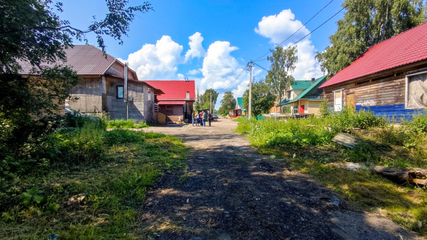Улица сельского поселка с домами и группой людей