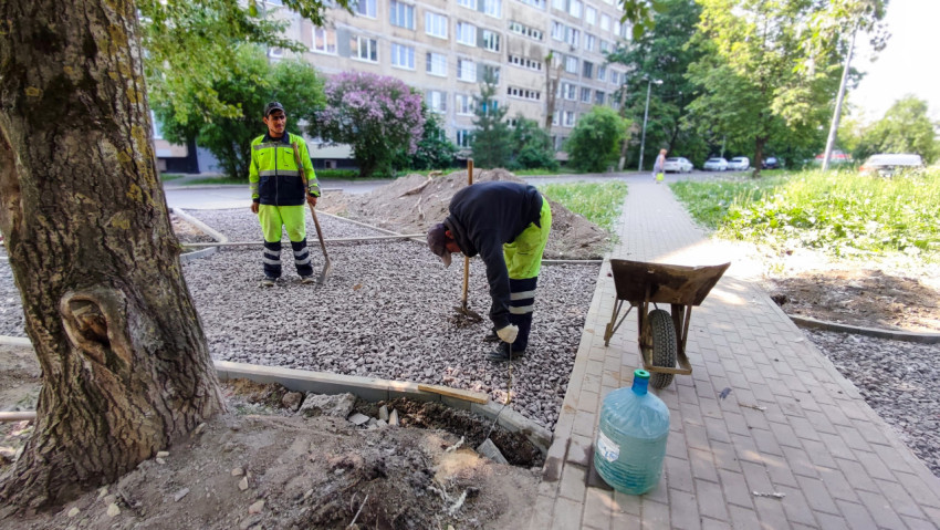 Рабочие проводят укладку гравия при благоустройстве двора