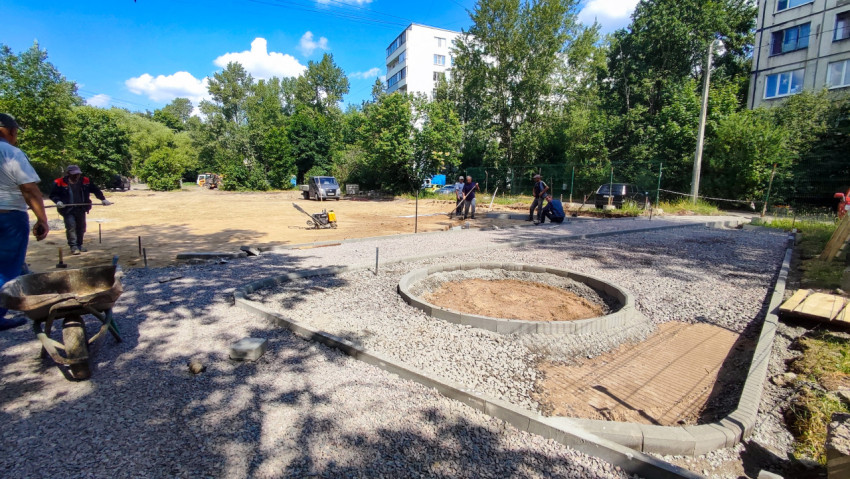 Рабочие укладывают основание из щебня для благоустройства двора