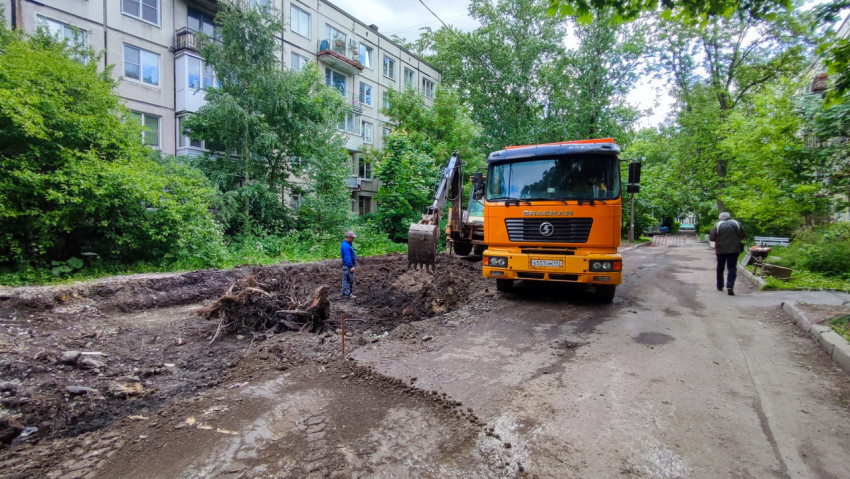 Экскаватор и самосвал во дворе жилого дома