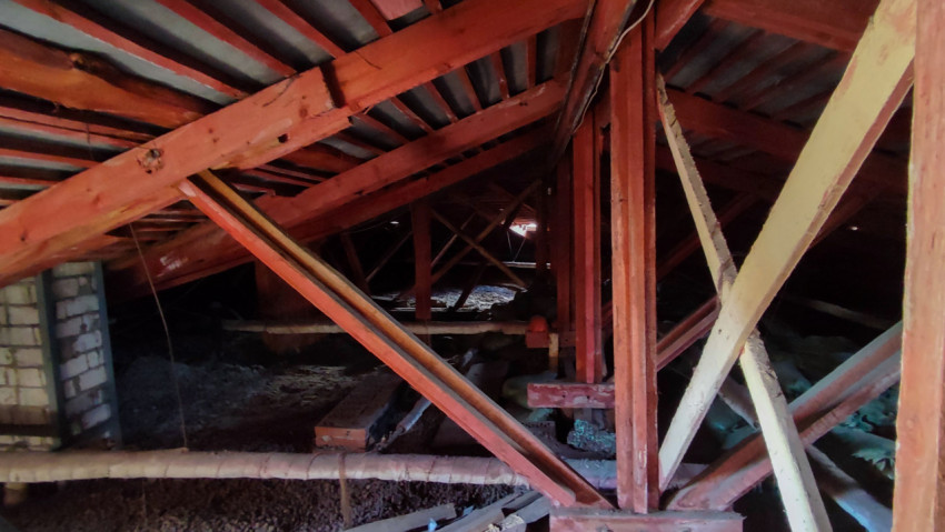 Чердак с деревянными стропилами и кирпичной стеной