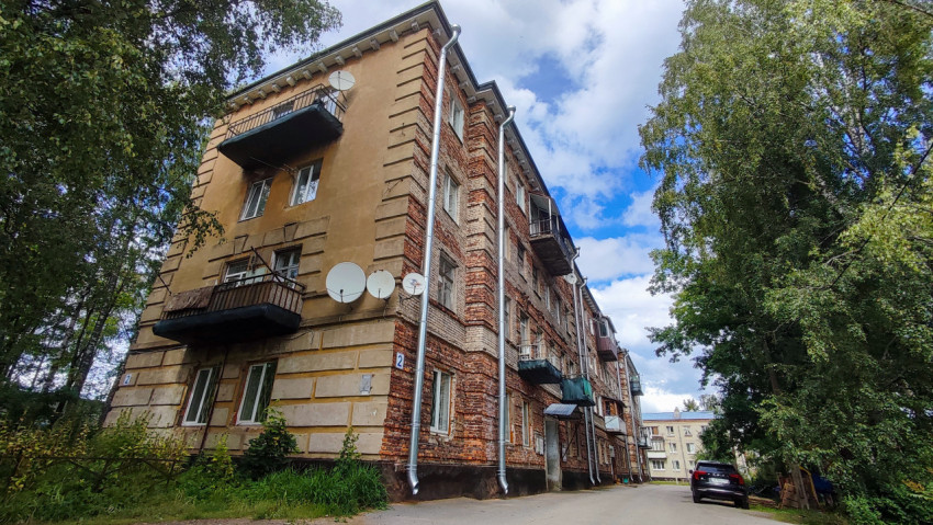 Фасад кирпичного жилого дома с балконами и антеннами