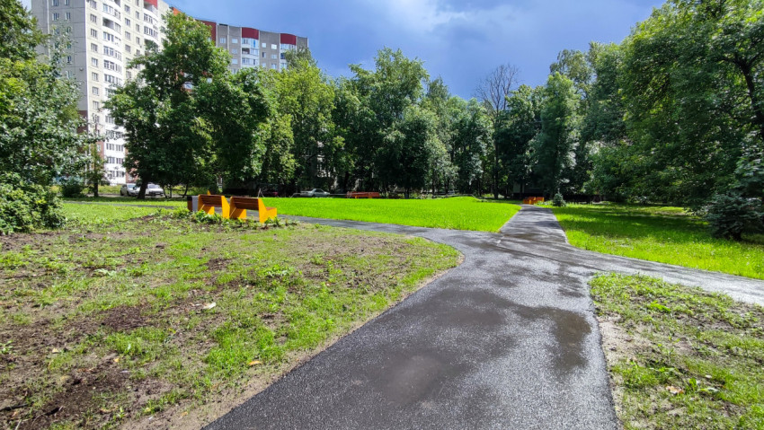 Асфальтированная дорожка и скамейки во дворе жилого квартала