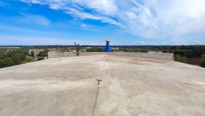Вид на бетонную кровлю с куполом православного храма на горизонте
