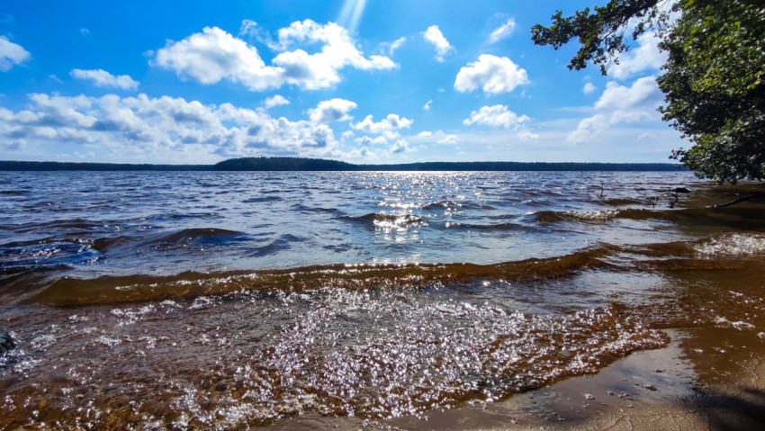 Прибой озера с волнами и солнечными бликами