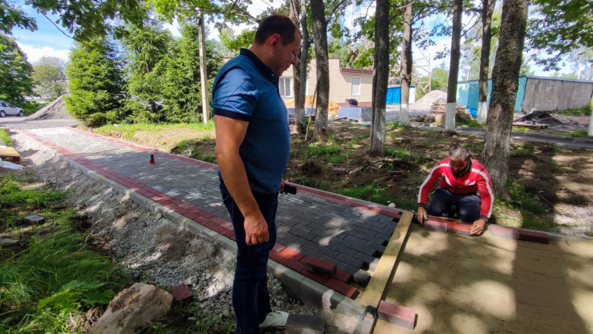 Рабочие укладывают тротуарную плитку во дворе