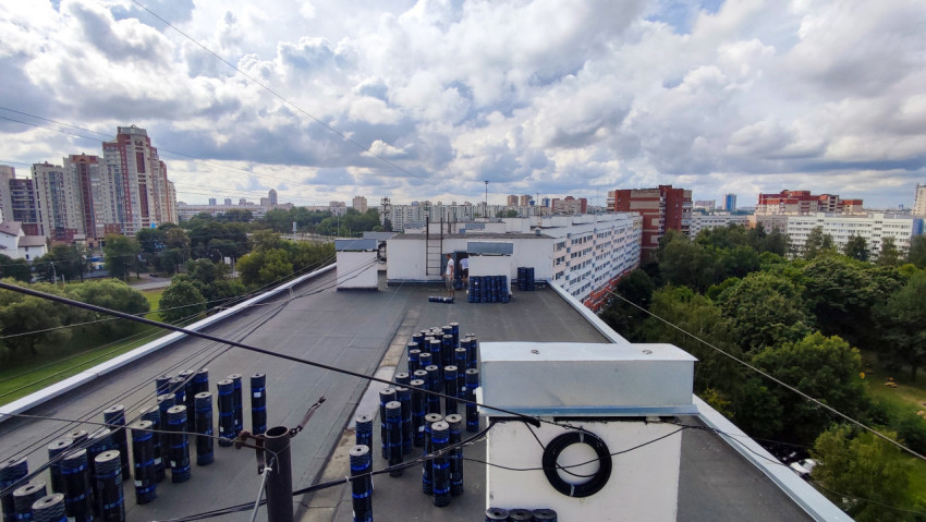 Вид на крышу жилого дома с рулонами кровельных материалов