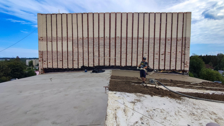 Рабочий на крыше во время укладки цементной стяжки