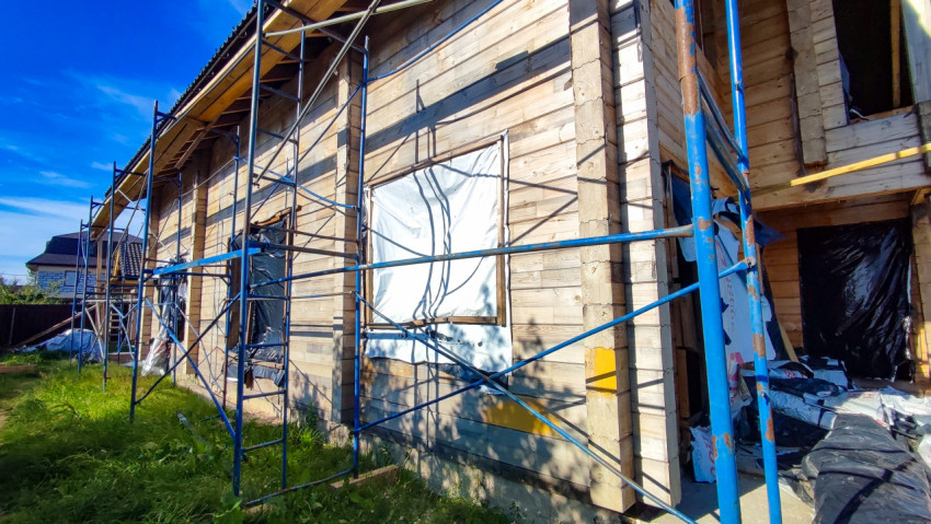 Строительные леса у стены деревянного дома