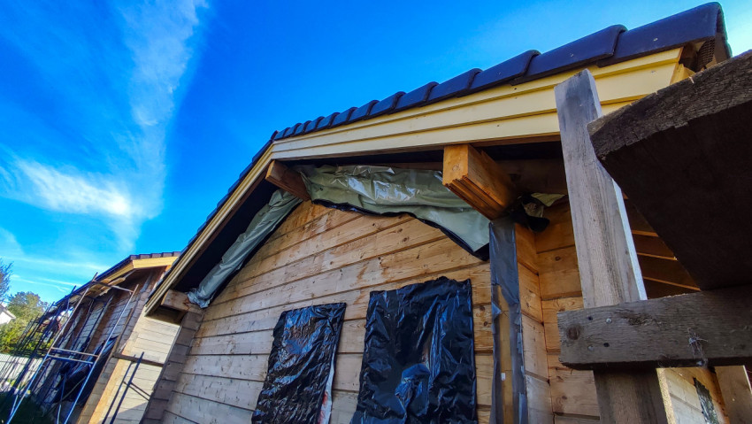 Фасад деревянного дома с установленной кровлей и временной защитой