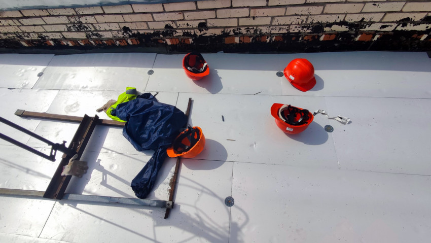 Красные строительные каски и спецодежда на крыше здания