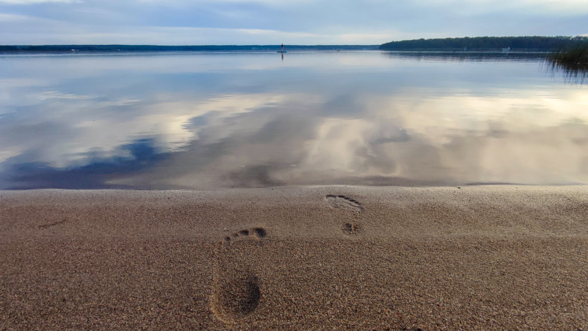 Следы босых ног на песчаном берегу у озера