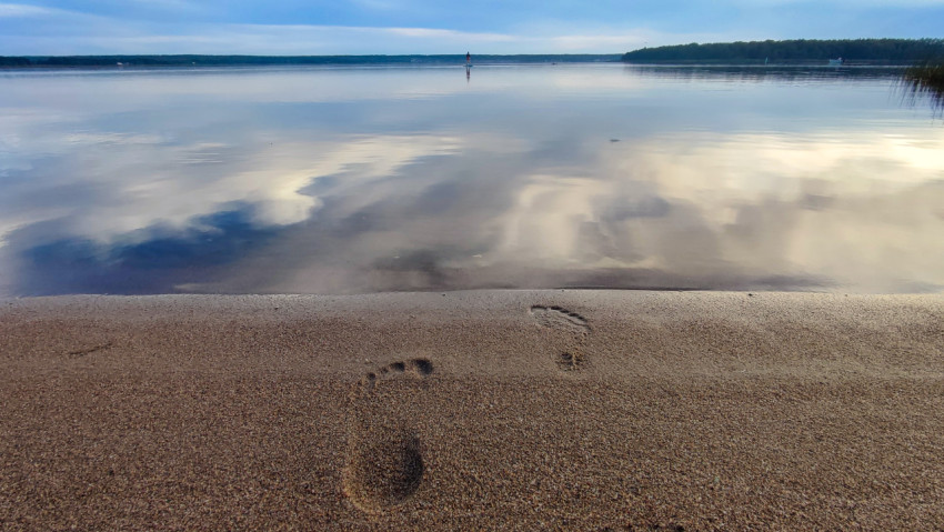 Следы босых ног на песчаном пляже у водоема