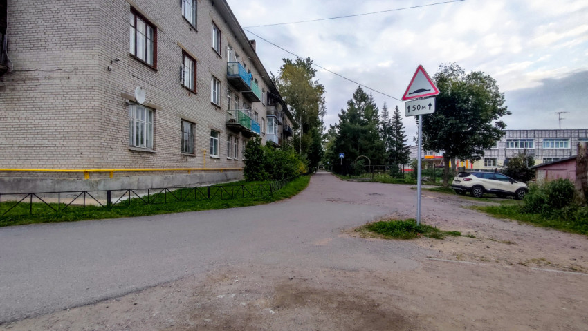 Дорога у жилого дома с предупреждающим знаком о неровности