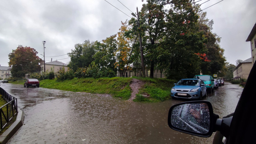 Осенний дождливый день в жилом квартале с лужами на дороге