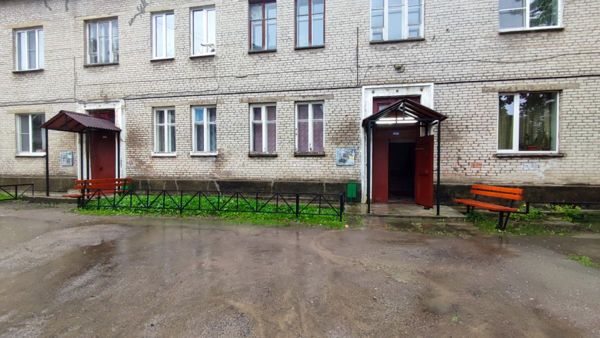 Фасад кирпичного дома с двумя подъездами и лавочками