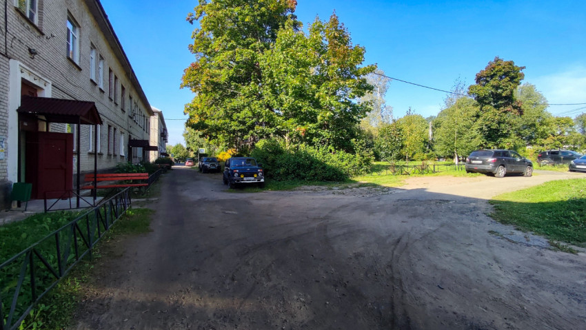 Дворовая дорога и жилые дома с припаркованными автомобилями