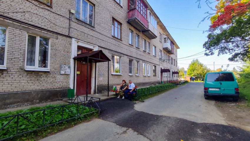 Двор жилого дома с отдыхающими жителями и припаркованным автомобилем