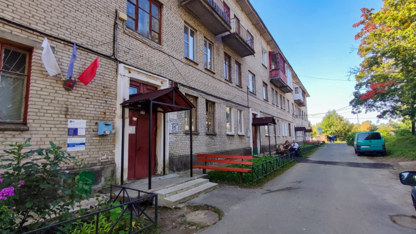 Вход в жилой дом советской постройки с флагами и лавочкой