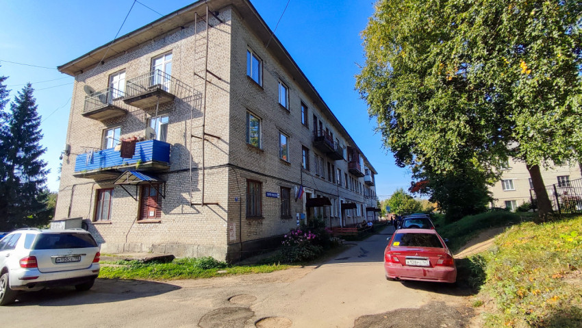 Кирпичный жилой дом с балконами и припаркованными автомобилями