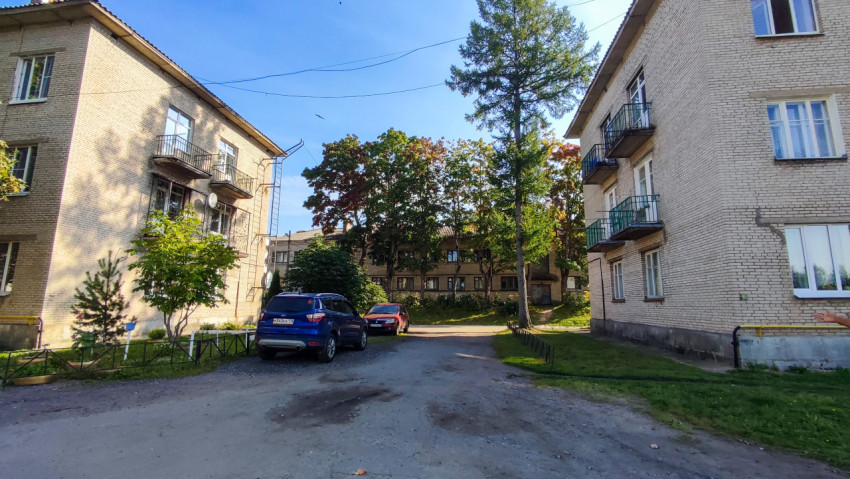 Двор между жилыми домами с припаркованными автомобилями и деревьями