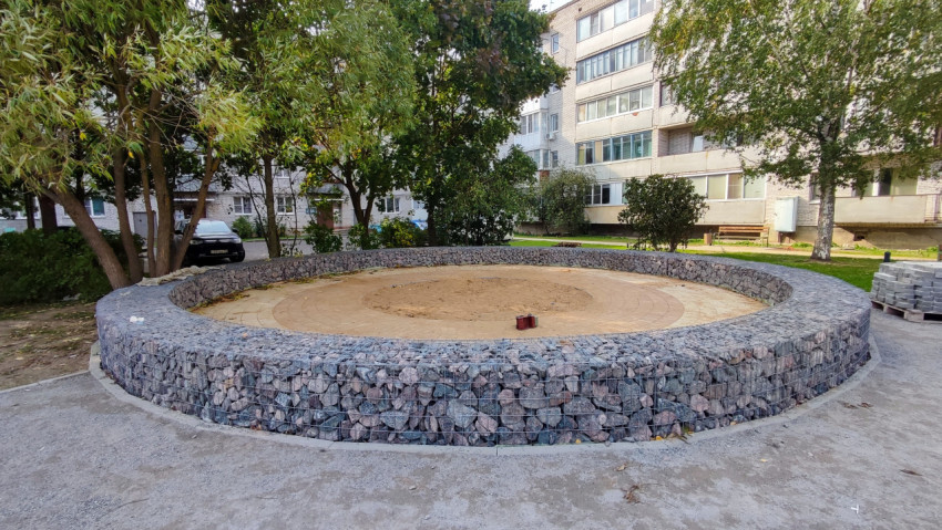 Круглая площадка из габионов с песчаным покрытием во дворе многоквартирного дома