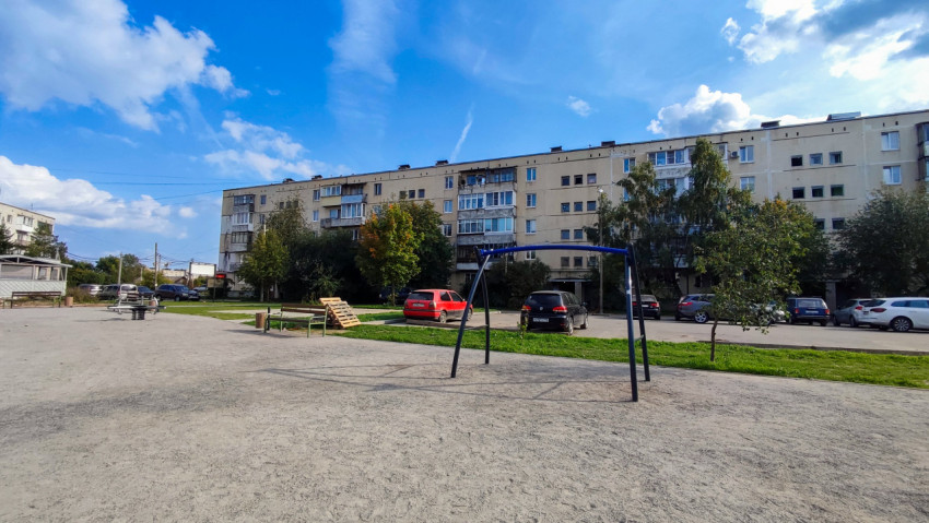 Игровая площадка с качелями и парковкой у жилых домов