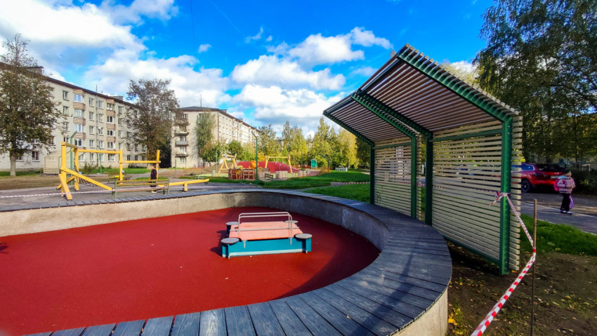 Современная детская площадка с навесом и зонами отдыха во дворе жилого квартала