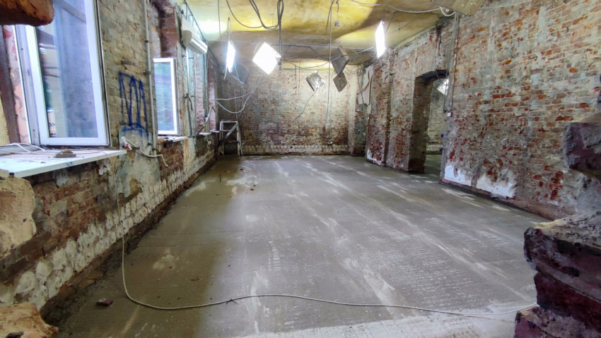 Помещение с обновлённой бетонной стяжкой и открытой кирпичной кладкой