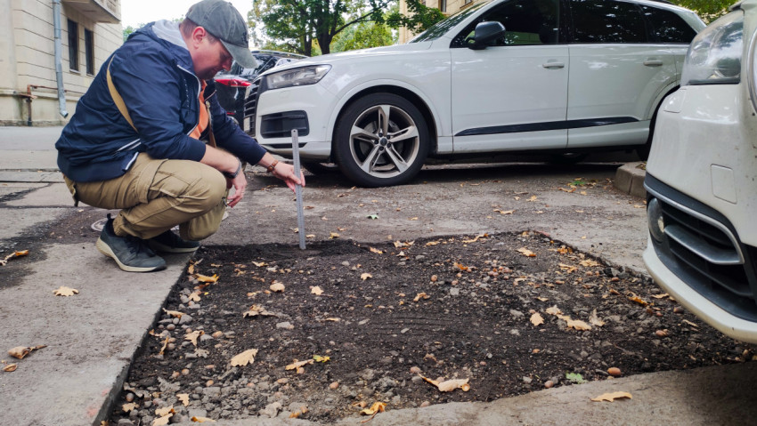 Инженер измеряет глубину выемки дорожного покрытия во дворе