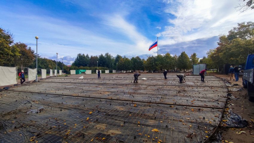 Рабочие укладывают арматурную сетку на строительной площадке