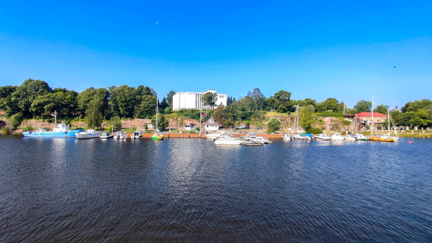 Вид на белое здание на холме и яхт-клуб у берега реки в Выборге