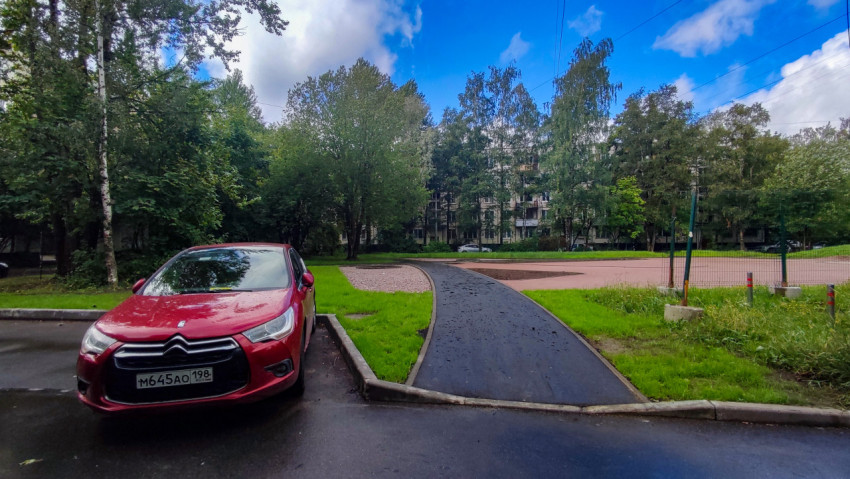 Асфальтированная дорожка у жилого дома и парковка автомобилей