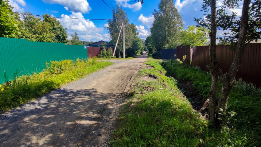 Грунтовая дорога с дренажной канавой и заборами