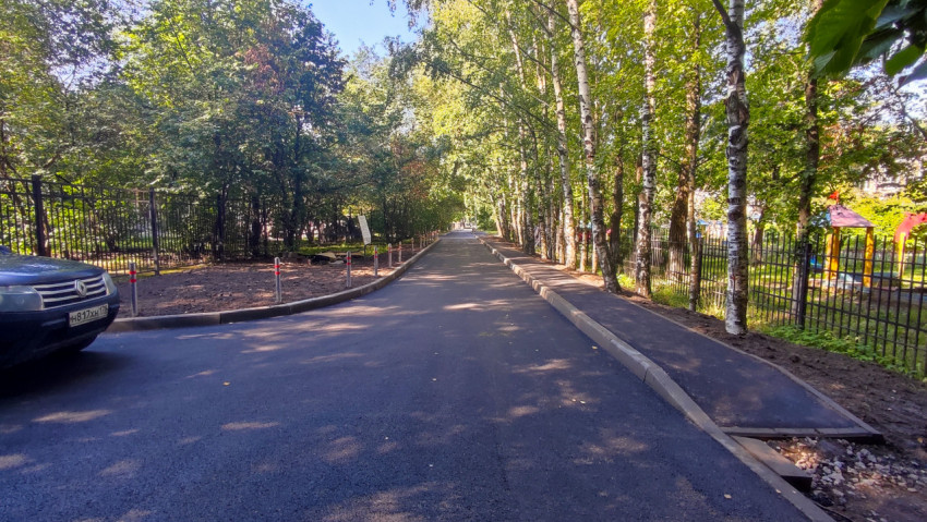 Асфальтированная дорога вдоль забора и деревьев