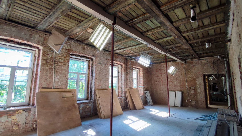 Помещение с окнами и фанерными листами на стадии ремонта