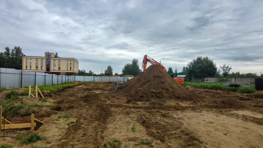 Экскаватор и земляные работы на огороженной площадке