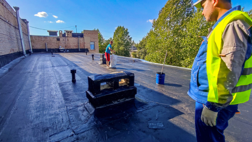 Рабочие на крыше во время укладки рулонной кровли