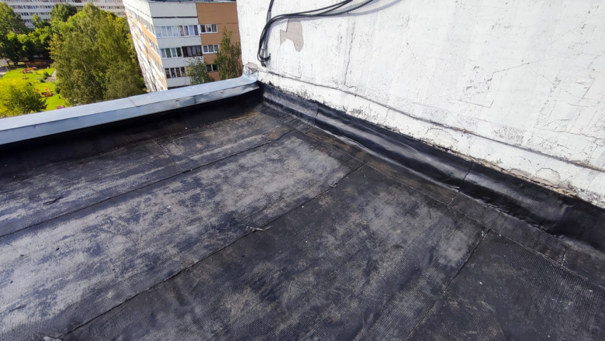 Участок крыши с новым рулонным покрытием и стеной