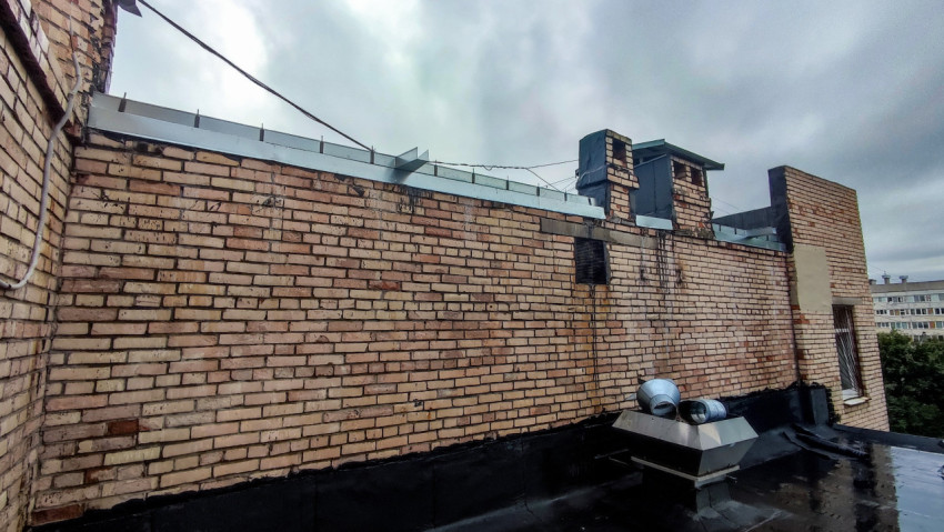 Кирпичная стена здания с вентиляционными выходами на крыше