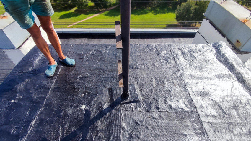 Человек на крыше рядом с антенной трубой