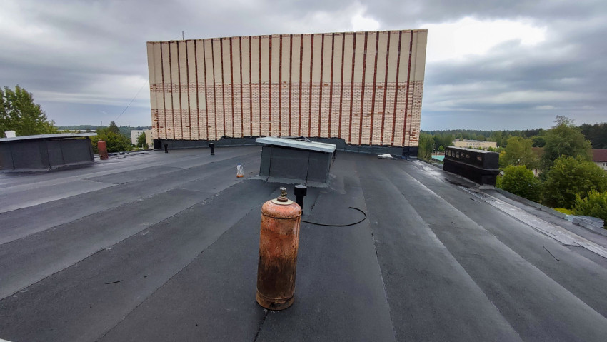 Плоская крыша здания с газовым баллоном и кирпичной стеной